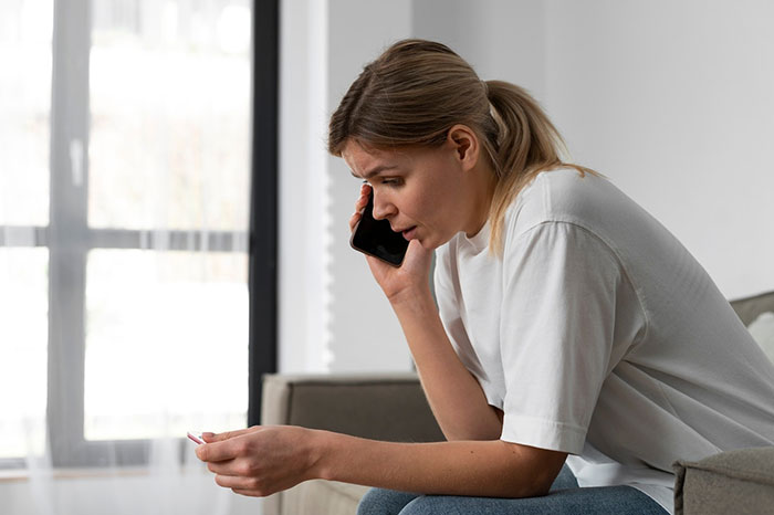Woman talking on phone, seated indoors, looking concerned. Woman talking on phone, seated indoors, looking concerned.