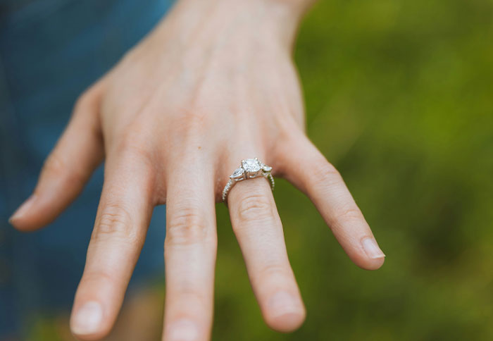 Close-up of a hand wearing a diamond ring, set against a green background, highlighting the keyword "real baby". Close-up of a hand wearing a diamond ring, set against a green background, highlighting the keyword "real baby".