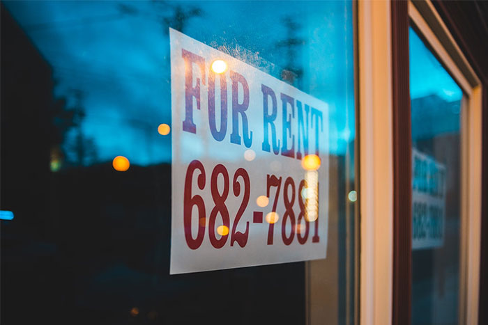 For rent sign with phone number reflected on glass window at dusk, highlighting timestamped pictures context.