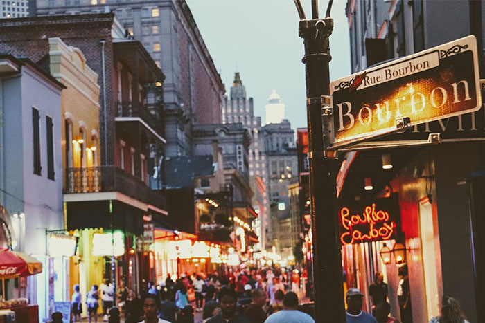 Crowded city street at dusk with illuminated signs and people walking, capturing timestamped pictures of urban life.
