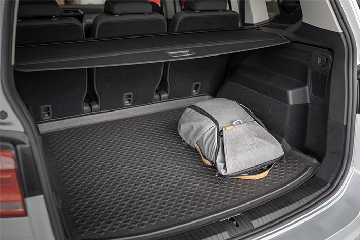 Car trunk with textured mat and gray backpack, illustrating random things people did that really saved them later.