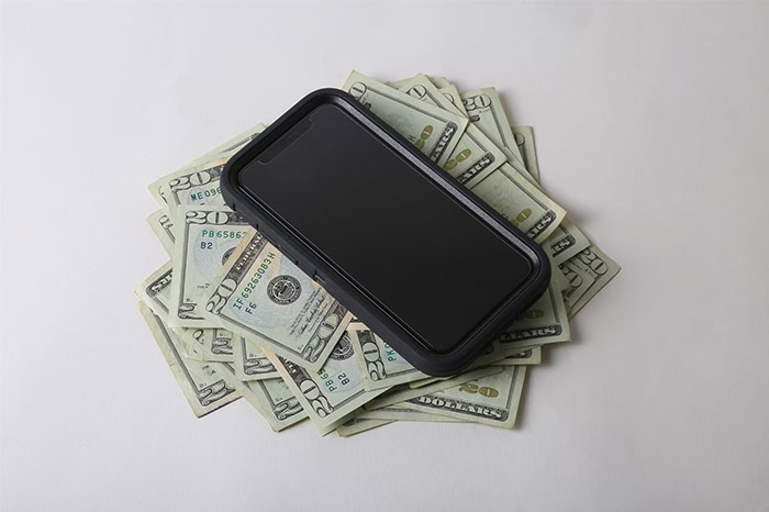 Smartphone placed on a pile of cash, illustrating a random act that really saved someone later.