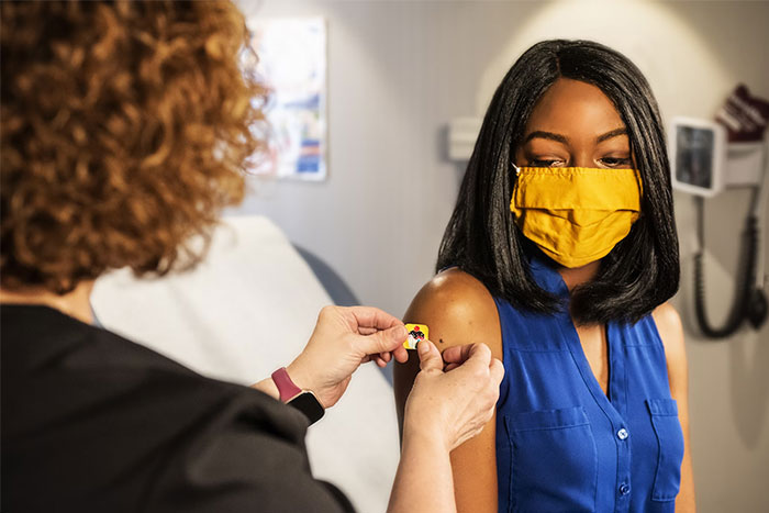 Woman in a yellow mask receiving a vaccination shot, one of the random things that really saved her later.
