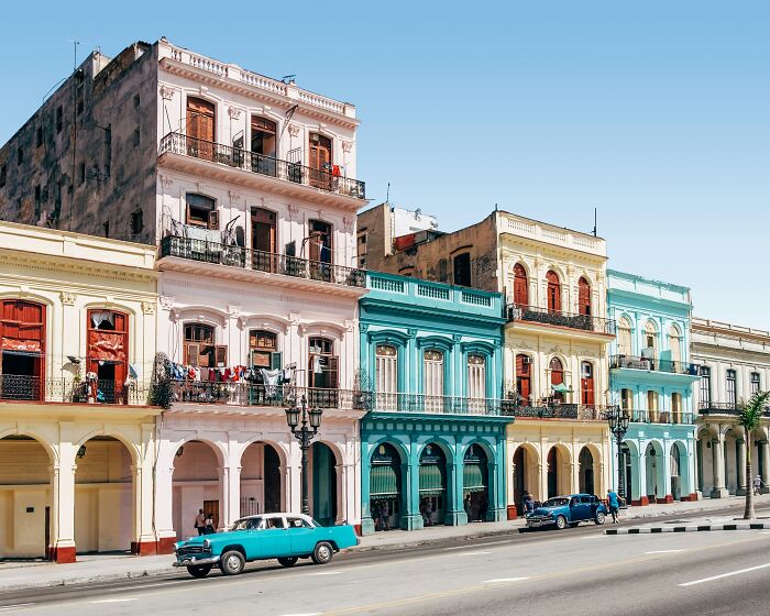 Colorful historic buildings on a sunny street with vintage cars, representing the worst country ever visited concept.