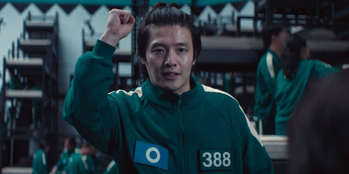 Man in green tracksuit number 388 from Squid Game, raising fist, possibly revealing Easter eggs or clues.