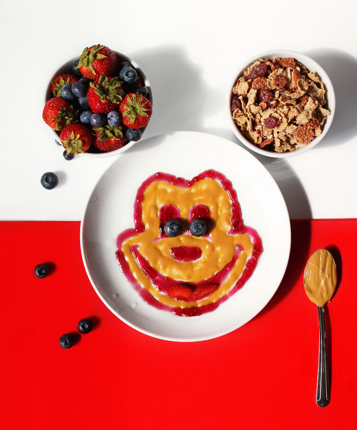 Cartoon-inspired food art with fresh ingredients like berries and cereal, creating a playful character face on a plate.