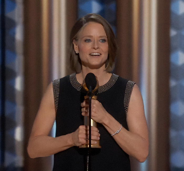 Jodie Foster holding a microphone on stage.
