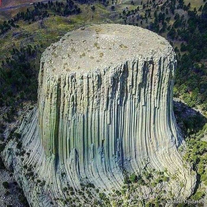 Aerial view of a fascinating rock formation resembling a massive, flat-topped tower in a forested landscape.