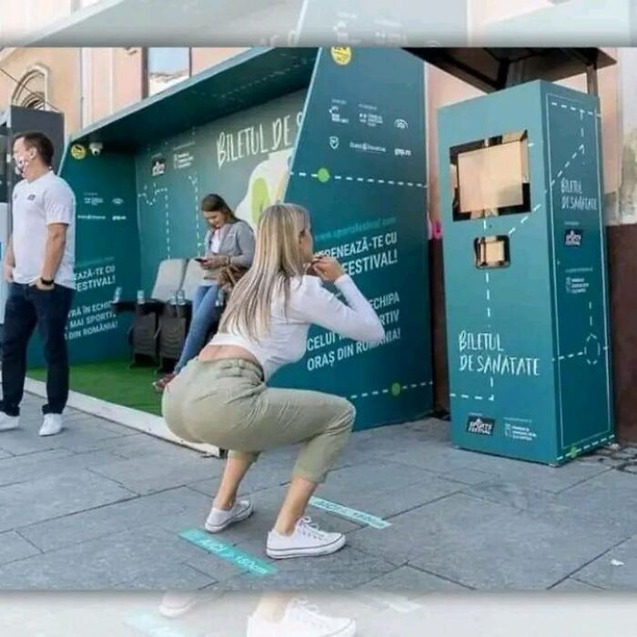 Woman squatting in front of a fitness kiosk, part of a fascinating interactive street setup promoting health awareness.