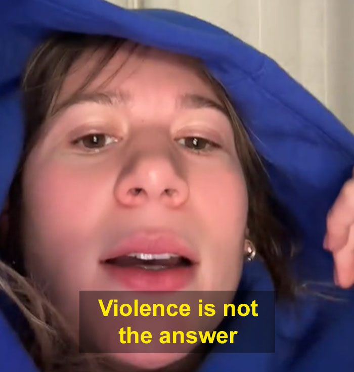 Person in a blue hoodie with "Violence is not the answer" text, discussing lack of sympathy for CEOs. Person in a blue hoodie with "Violence is not the answer" text, discussing lack of sympathy for CEOs.