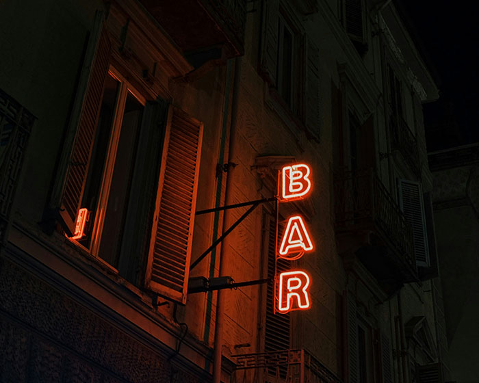 Neon bar sign glowing at night, hinting at dark secrets and confessions.