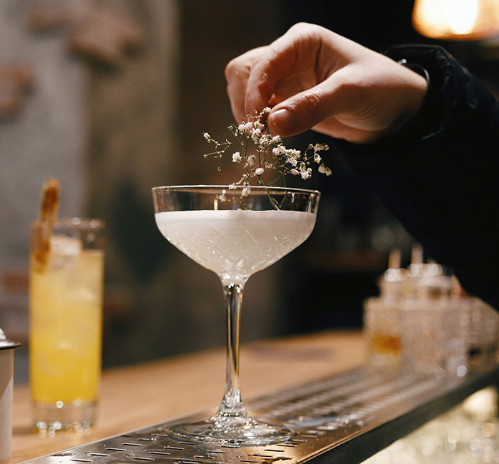 Elegant cocktail garnished with a flower at a dimly lit bar, representing dark secrets shared while drunk.