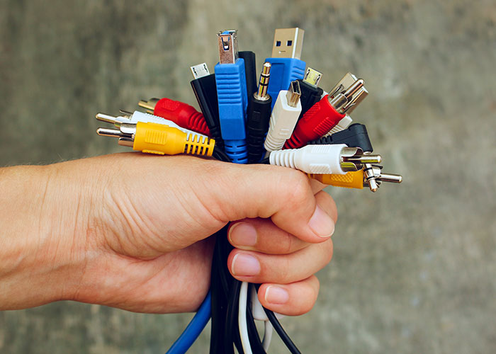 A hand holding various colorful audio and USB cables.