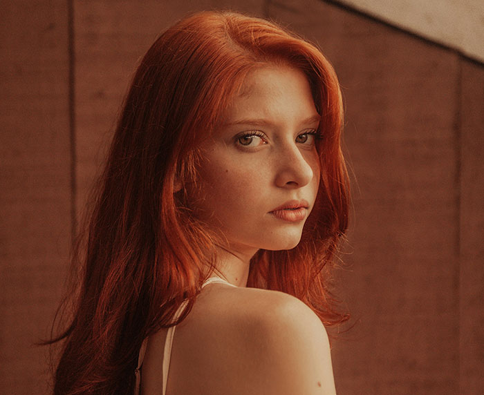 Red-haired woman gazing back thoughtfully, highlighting subtle emotions related to "creepy things men do."