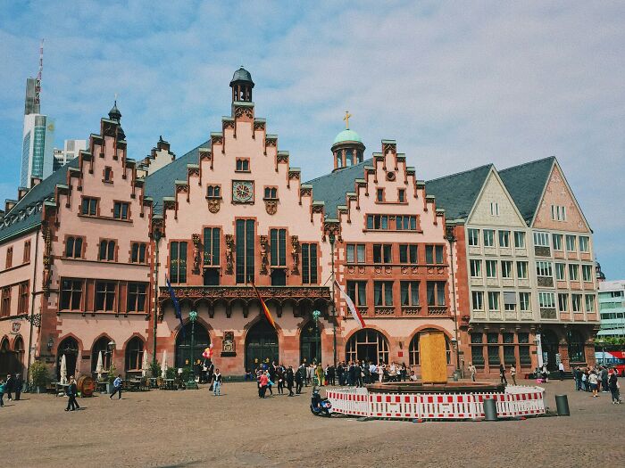 Historic building with tourists in a European city square, symbolizing a travel experience in the worst country ever visited.