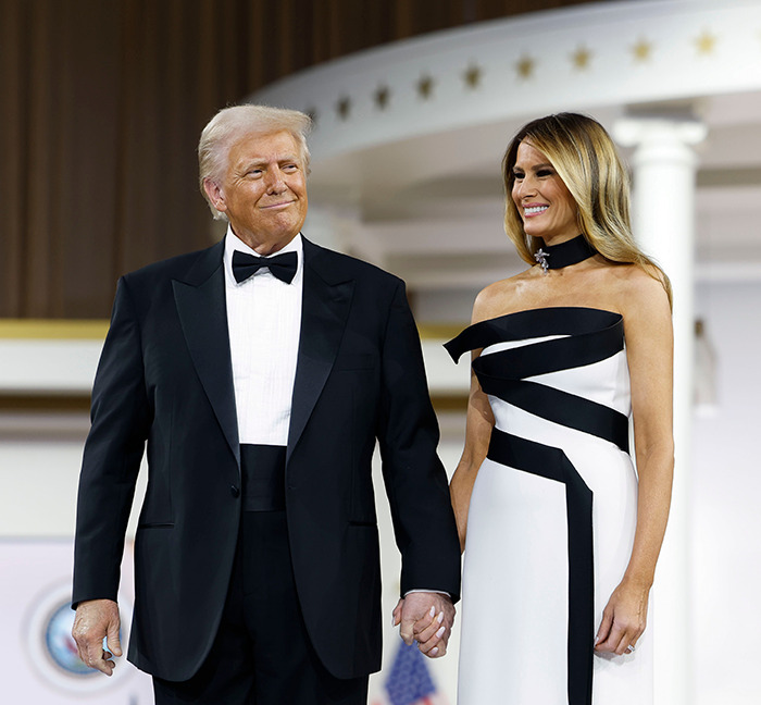 Donald Trump and Melania Trump holding hands in formal attire at the inauguration.
