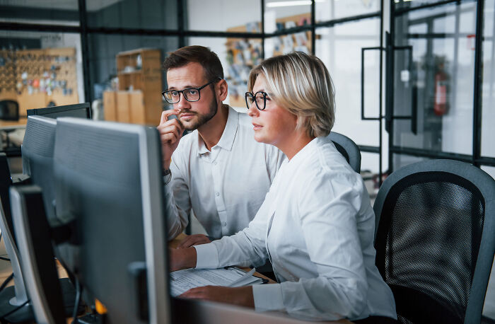 Two professionals in a modern office setting working on high-paying remote jobs, focused on computer screens.