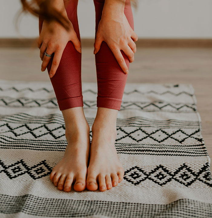 Person in leggings touching toes on a patterned mat, illustrating unwritten hotel etiquette practices.