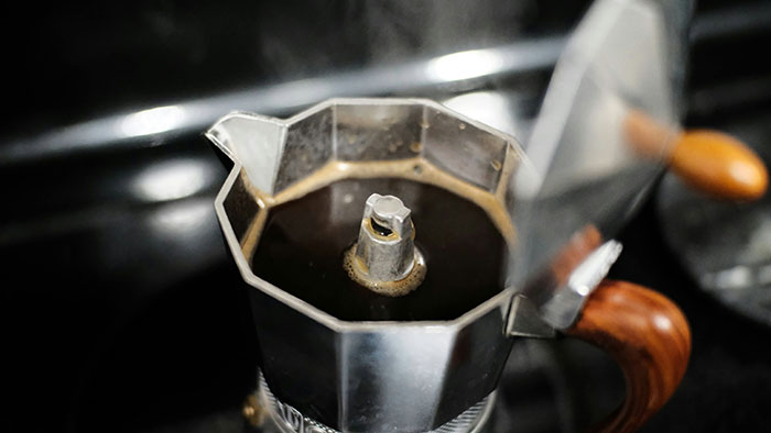 Stovetop coffee maker brewing in a hotel room, highlighting unspoken travel rules.