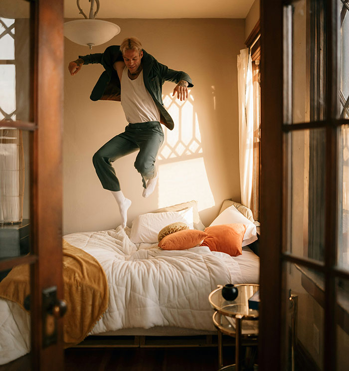 Person jumping on a bed in a hotel room, illustrating unspoken hotel etiquette.
