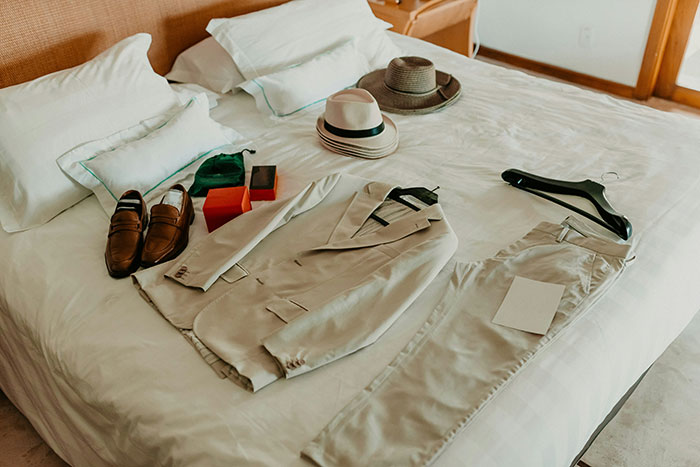 Clothing and accessories neatly arranged on a hotel bed, reflecting unspoken hospitality rules.