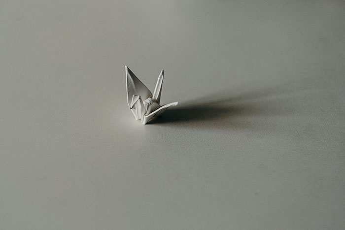 Origami crane on a smooth gray surface, reflecting attention to detail like unspoken rules in hotels.