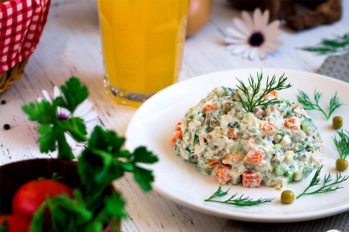 Plate of Russian salad with dill, peas, and orange drink, linked to urban legends cuisine flair.