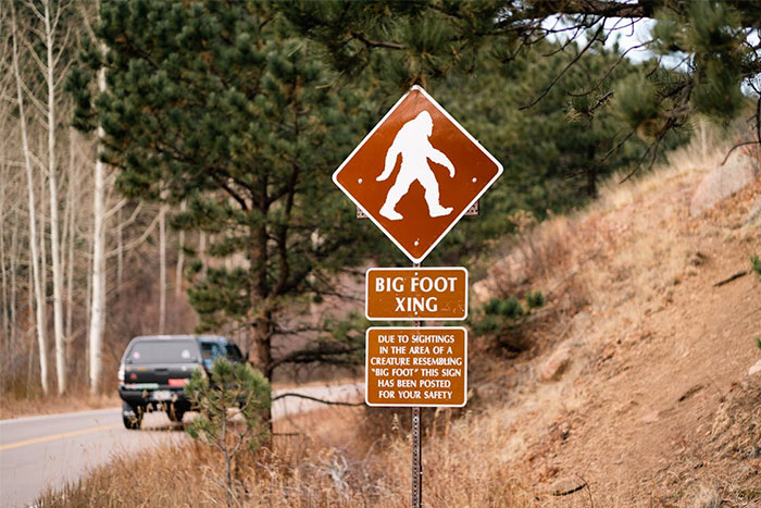 Bigfoot crossing sign on a rural road, illustrating urban legends about Bigfoot sightings in the area.