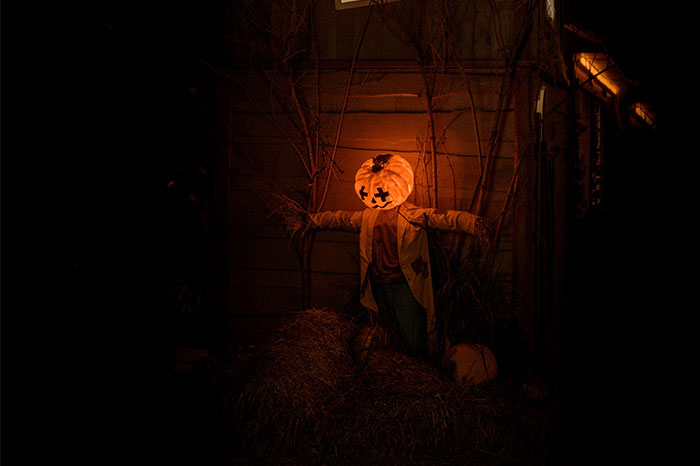 Scarecrow with a glowing pumpkin head at night, reflecting eerie urban legends.