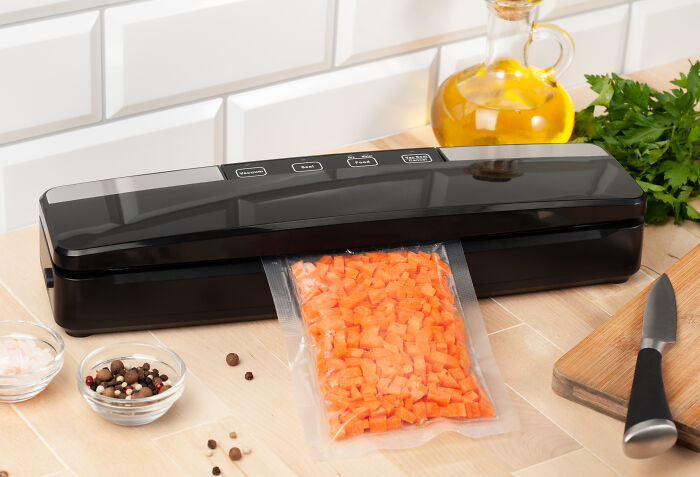 Vacuum sealer packaging diced carrots, a money and space-saving kitchen device on a countertop.