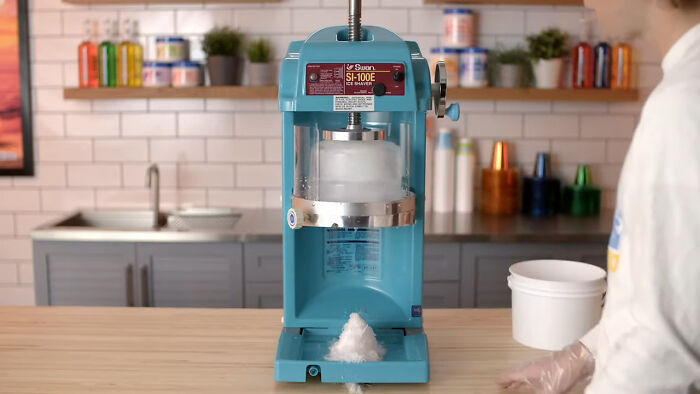Affordable ice shaver machine on a kitchen counter, with snow-like ice, showcasing a simple way to make life easier.