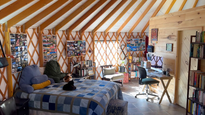 Interior of a self-built yurt with bed, desk, and bookshelves, showcasing off-grid lifestyle details. Interior of a self-built yurt with bed, desk, and bookshelves, showcasing off-grid lifestyle details.