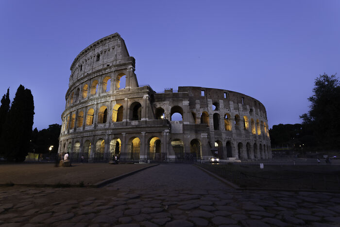 Colosseum in Rome at dusk, illuminated against a twilight sky, showcasing historic architecture in Italy.