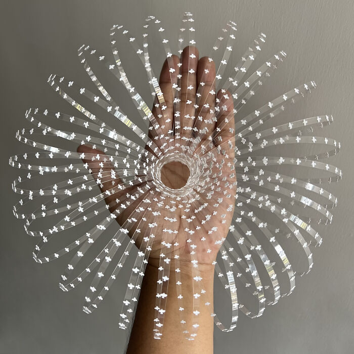 Intricate paper cut design shaped like a floral pattern held against a hand, showcasing tree-less existence artistry.