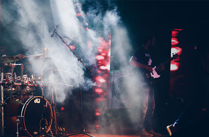 Musicians performing on stage with dramatic lighting and fog.