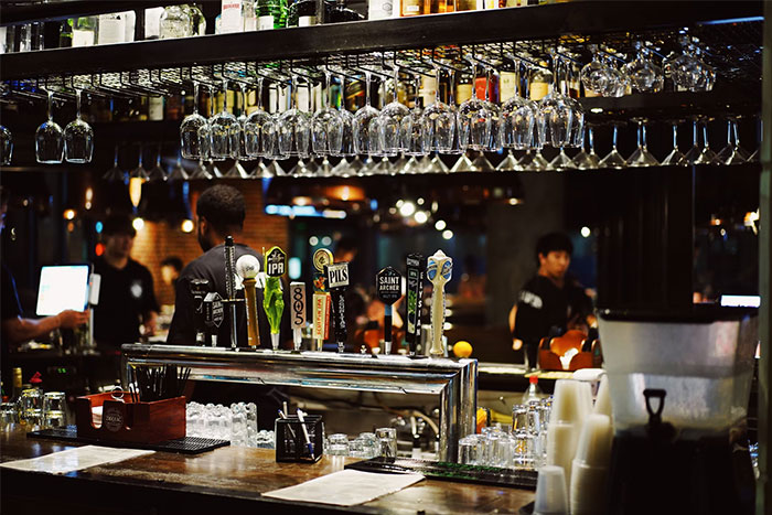 Bar interior with bodyguards at work, surrounded by hanging glasses and tap beers, creating a secure environment.