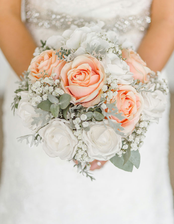 Bride holding a bouquet of pink and white roses; focus on arranged marriage theme.