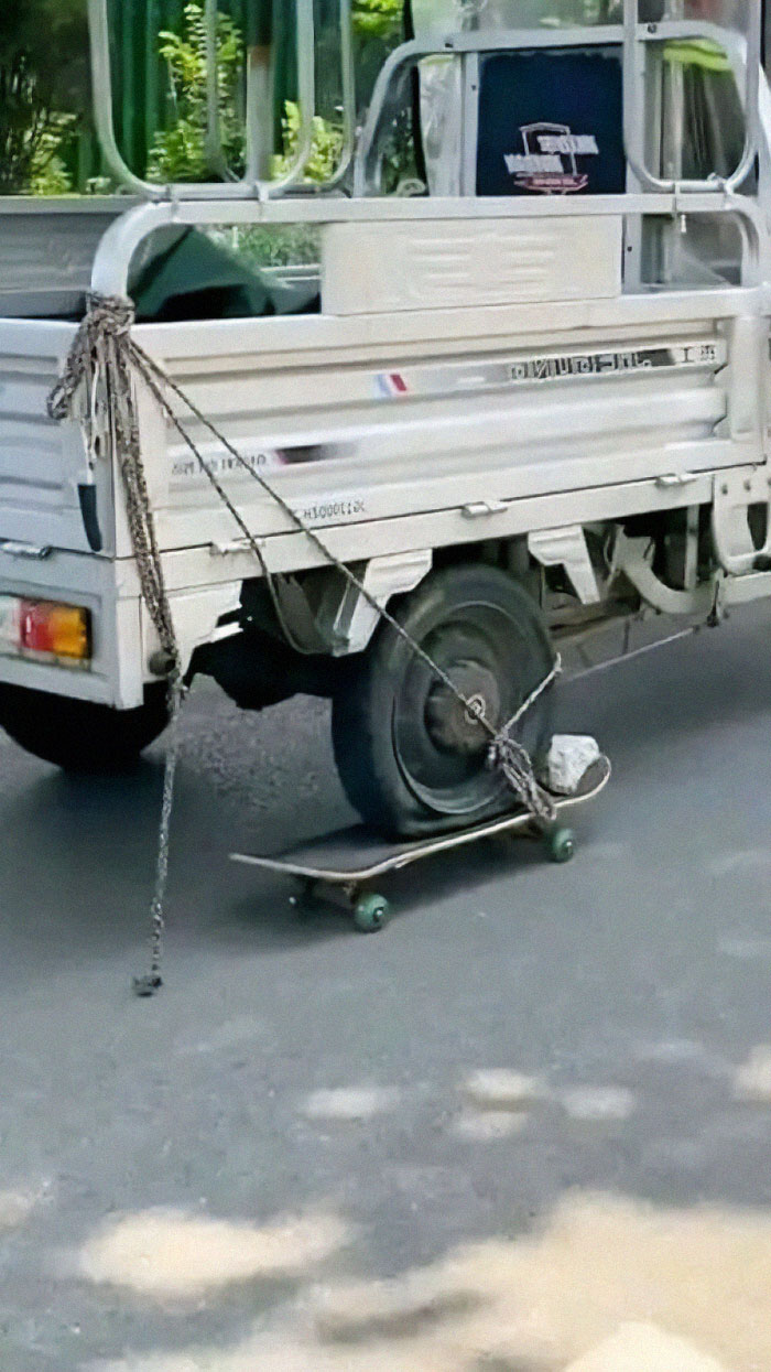 Bizarre image of a truck wheel secured on a skateboard with chains.