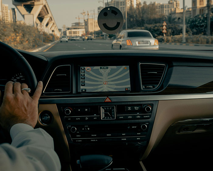 "Driver's view inside car with GPS, navigating city streets while driving for wealthy clients."