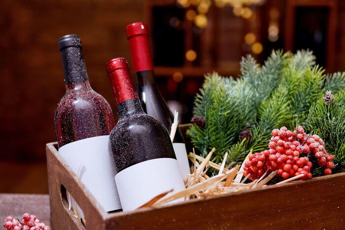 Wine bottles in a wooden box with pine branches and berries.