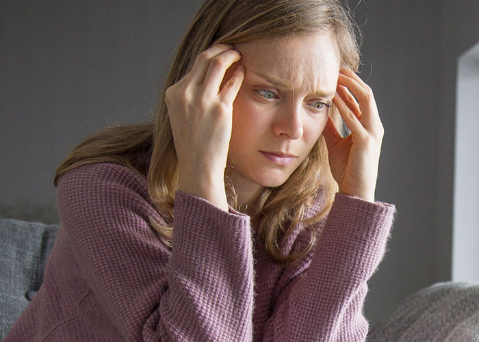 Woman in a purple sweater looking stressed, representing family betrayal.