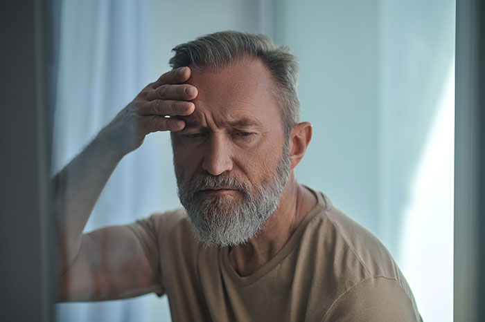 Man with a thoughtful expression, hand on forehead, illustrating neurodivergent husband.