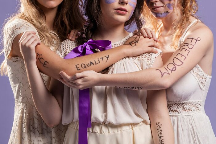 Three women with words like equality and freedom written on their arms, symbolizing history and social justice facts.