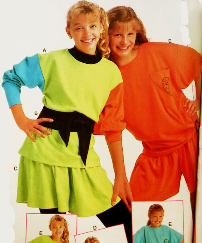Two girls in bright 80s fashion trends, one in a neon green outfit with a black belt, the other in an oversized orange top.