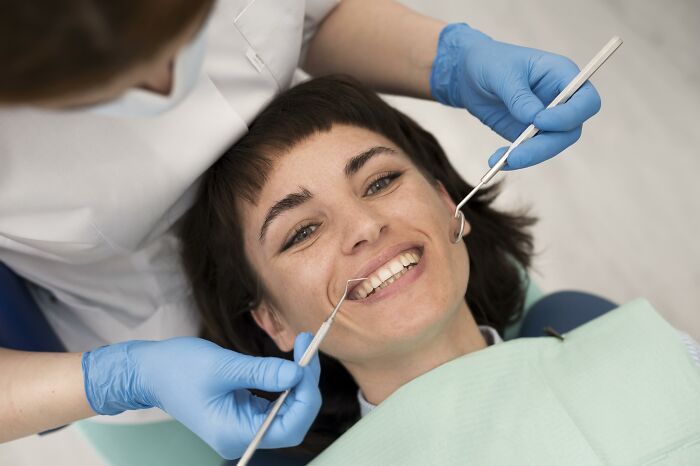 Person receiving dental care, which is slowly becoming unaffordable for the middle class, smiling during the check-up.