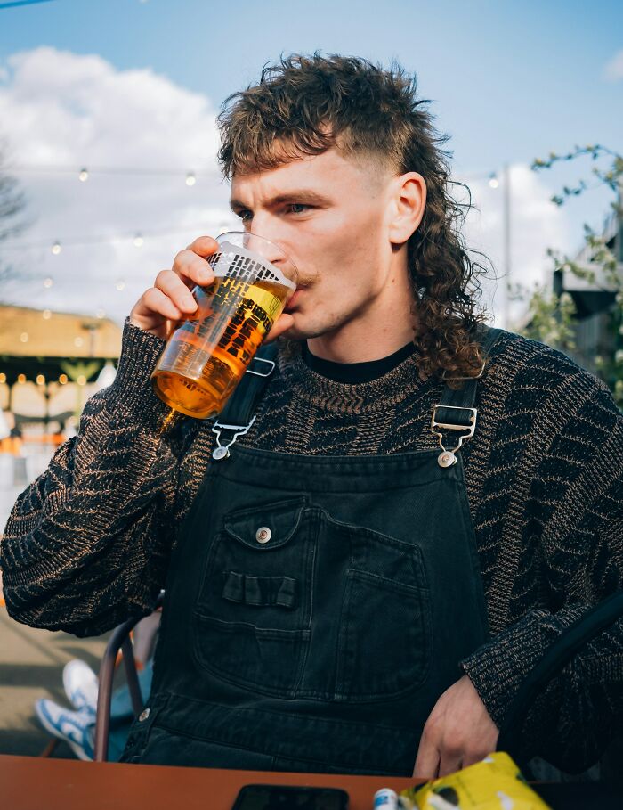 A person with a mullet drinks beer outdoors, showcasing laid-back home rules.