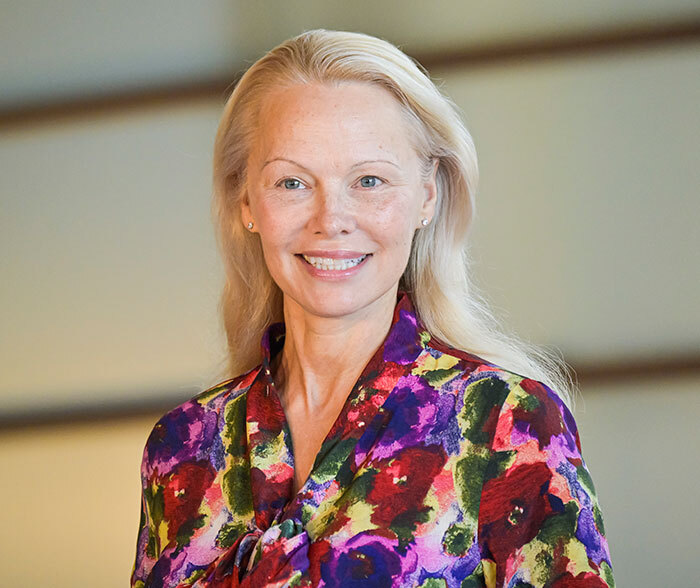 Celebrity without makeup, smiling in a colorful floral blouse.