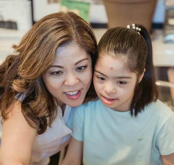Woman and child smiling together, highlighting assumptions about people’s jobs and roles in caregiving.