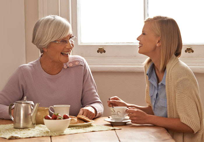 Two women sharing tea and laughter, reflecting on friendship and inheritance discussions.