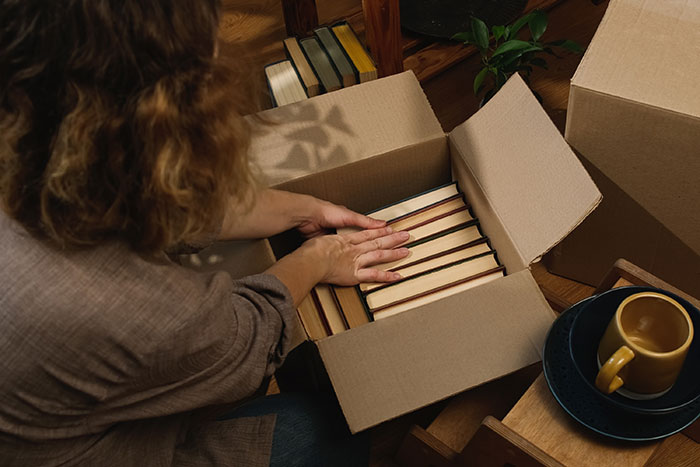 Person packing books into a box next to a mug, related to inheritance discussion.